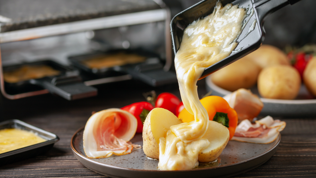 Raclette mit geschmolzenem Käse über Kartoffeln und Gemüse, perfekt für Fondueplausch und Erlebnisgastronomie in der Ostschweiz